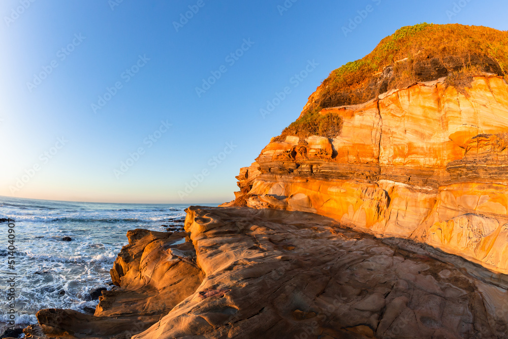 Beach Ocean Coast Large Sandstone Rocky Cliff In Morning Blue Sky Sunlight Colors A Scenic Landscape.