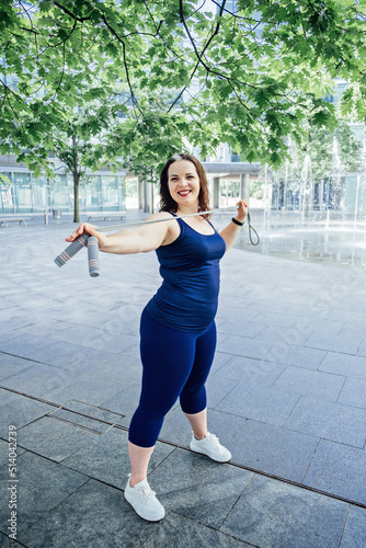 Confident Plus size curvy happy young woman doing exercise workout with skipping rope outdoors.