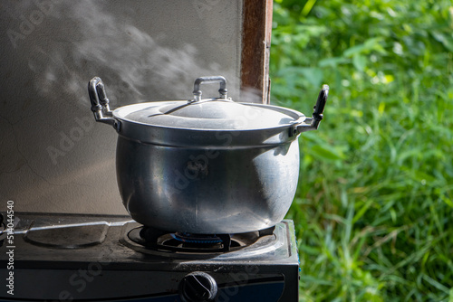 Preparing food by cooking in a pot on the stove next to an open door to a garden