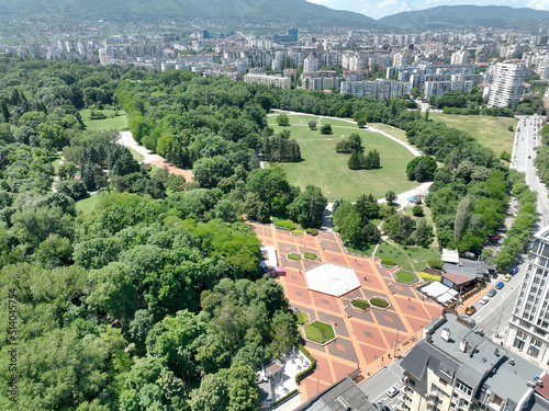 Park with arranged cobblestones in the shape of rhomboids. A fountain in the shape of an octagon. Green trees. South Park. View from above.