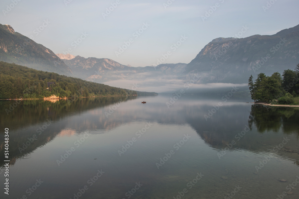 Beautiful forest reflection in the Bohinj lake with surrounding mountains