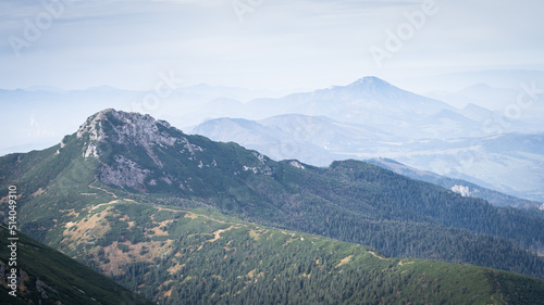 Rocky mountain surrounded by a forest with more mountains in fog in the background,Slovakia, Europe