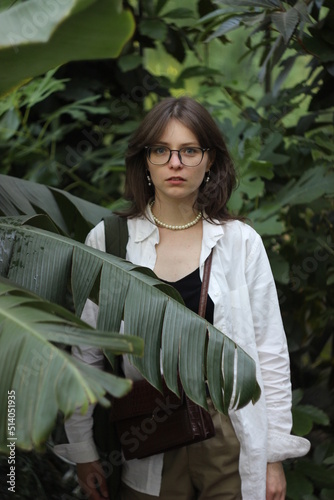 A girl with glasses in a green tropical forest