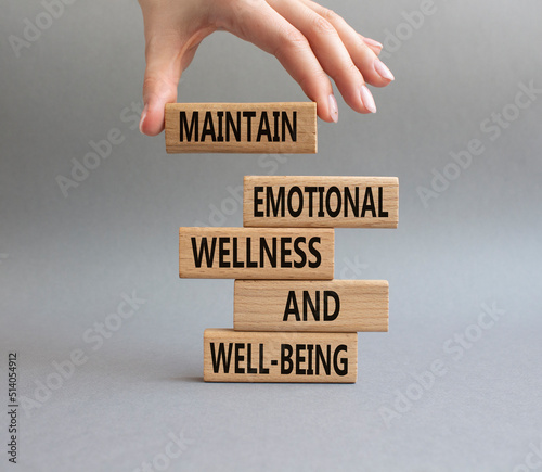 Wellness and Well-being symbol. Wooden blocks with words Maintain emotional Wellness and Well-being. Beautiful grey background. Businessman hand. Copy space