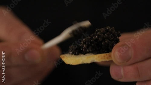 Spoon with black caviar in man hand. Luxurious delicacy. The cook makes sandwiches with black caviar. photo