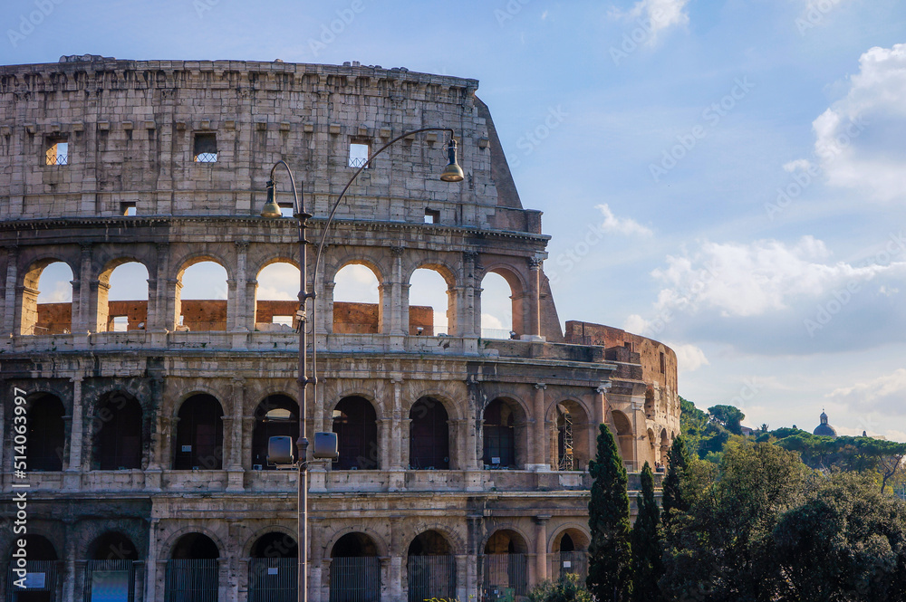 Front view of ancient Colosseum landmark of Rome, Italy, on a sunny and partly cloudy summer day.