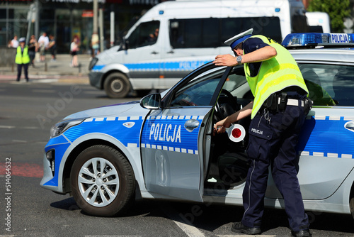 Policjant ruchu drogowego z lizakiem do zatrzymywania pojazdów w mieście kontroluje ruch na zabezpieczeniu. 