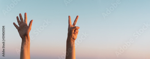 Woman hands showing or doing number seven gesture on blue summer sky background. Counting down, seven fingers up concept idea. Large copy space for text for displays, prints, advertising banners.