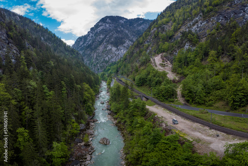 Drone aerial view of wild river Enns in cloudy weather in Gesause National Park near town of Admont in centre Austria. Visible long valley, clear blue water, road and railway.