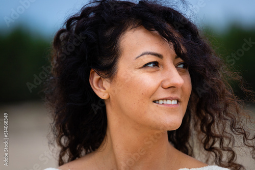 Portrait of a smiling woman with curly hair  brown skin  flowing hair.