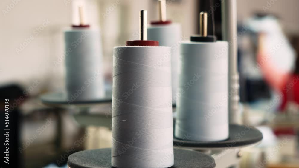 The thread is unwound from the spool while sewing by a seamstress on a sewing machine