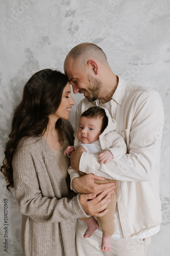 Mother and father holding their infant in minimalism interior small cute baby and stylish happy family with modern look