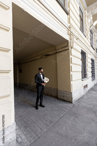 groom waiting a bride with flowers. man standing with flowers © Anton