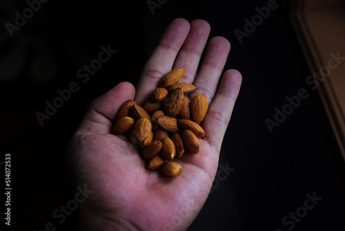 Hand holding a bunch of almonds. Healthy eating, almond on hand, nutritious food concept.