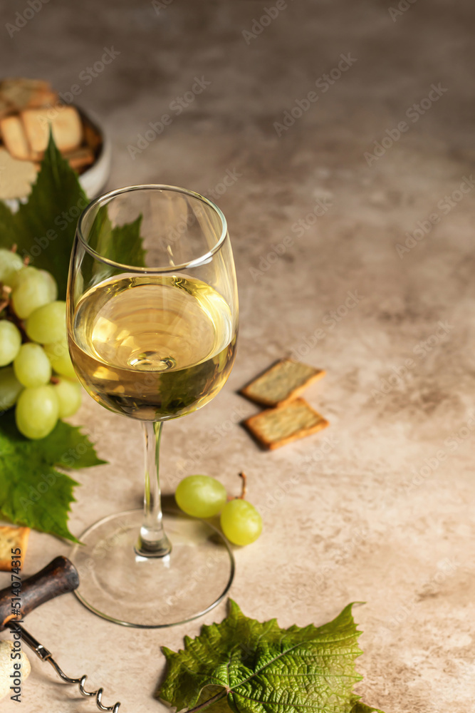 Glass of white wine on textured background with corkscrew and cork, grapes and crackers