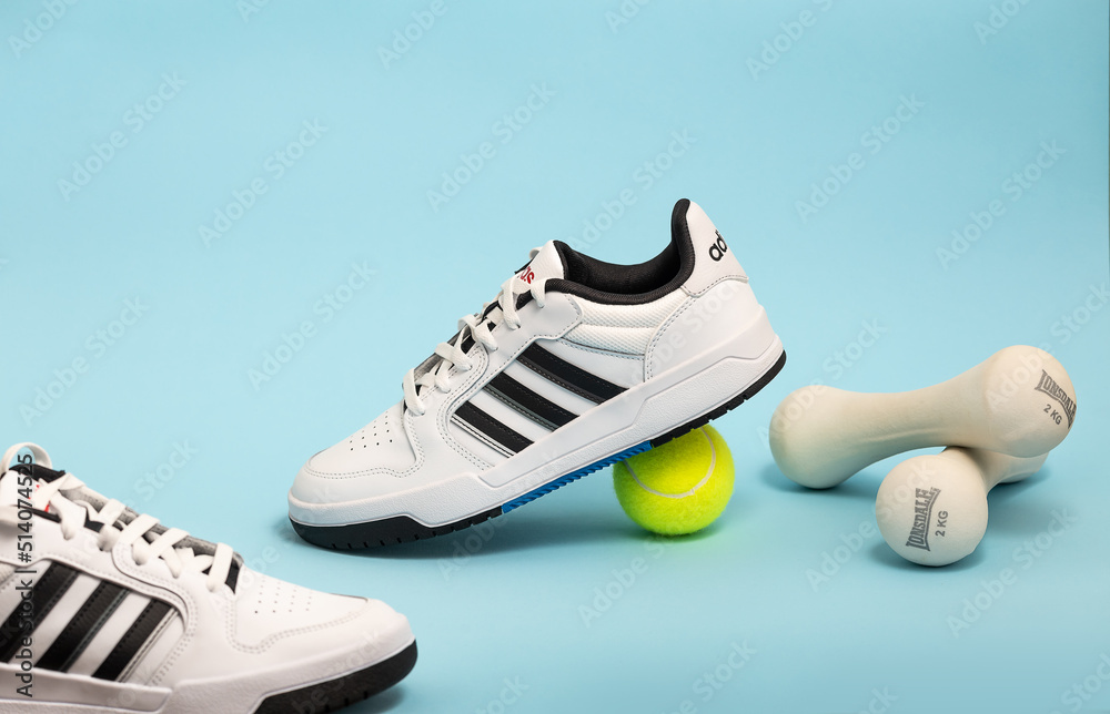 Belgrade, Serbia - May 11, 2022. New Adidas tennis shoes on blue background  with tennis balls. New Adidas Sneakers or trainers on blue background.  Men's sport footwear. Stock Photo | Adobe Stock