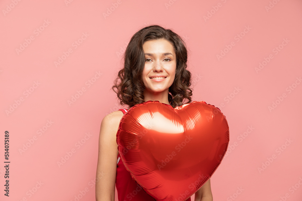 Portrait of young lady stands on pink background with heart shapped decoration Portrait of young lady stands on pink background with heart shapped decoration