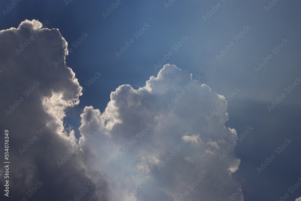 Blue sky background with sun rays behind the clouds. Blue sky background with sun rays behind the clouds.