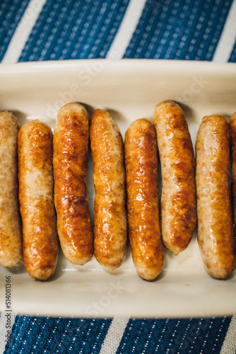 browned, cooked individual breakfast sausage links in white dish on blue and white stripe cloth