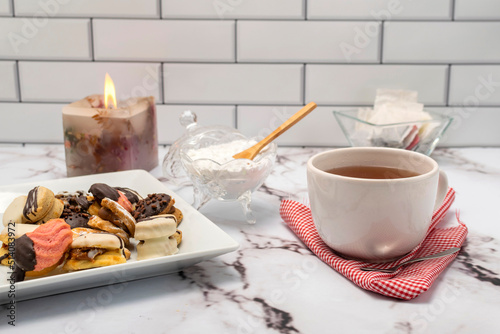 breakfast or snack with a cup of tea fine doughs of cornstarch chocolate vanilla and dulce de leche on a marble table with sugar bowl and decorative candle