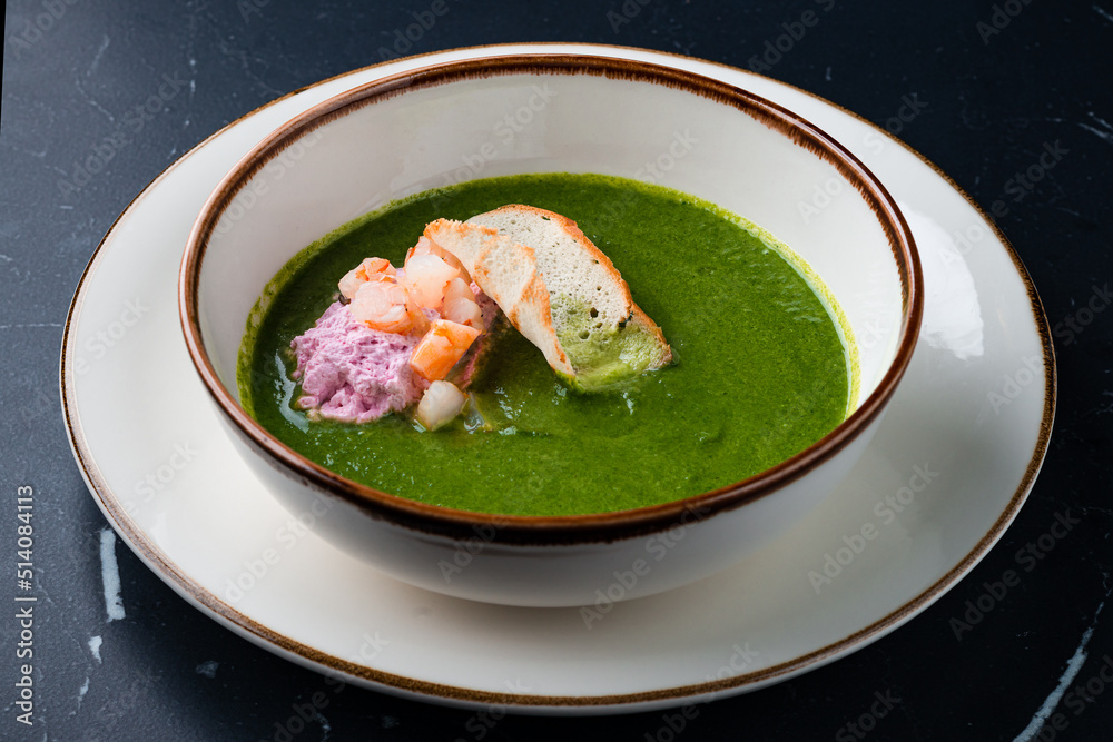 Broccoli, spinach cream soup with shrimp in a white bowl Broccoli, spinach cream soup with shrimp in a white bowl