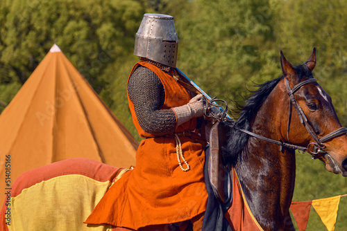 Knight in armor on a horse. Defender on guard. Brown warhorse with rider.