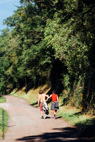 un couple de jeunes adultes marchant sur une route de campagne. Des jeunes amoureux en balade en été.