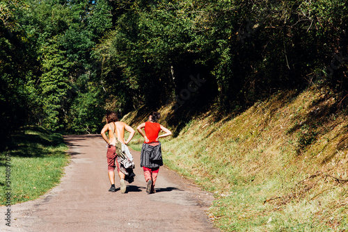 un couple de jeunes adultes marchant sur une route de campagne. Des jeunes amoureux en balade en été.