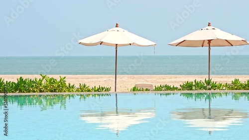 Wallpaper Mural Tops of beach umbrellas' heads pop over the edge of a resort swimming pool reflecting in water Torontodigital.ca
