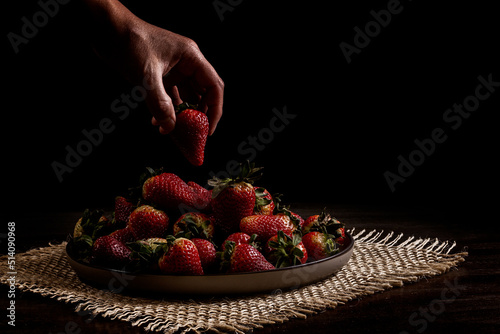 Close-up of a hand placing strawberries on a plate