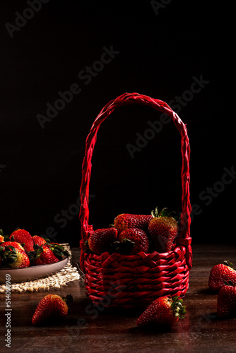 Strawberries in a red basket on a wooden table