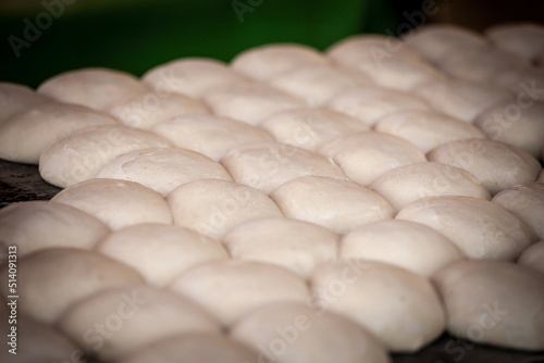Selective focus on raw dough, fresh and uncooked bread buns, ready to be baked, in bulk, by a baker...
