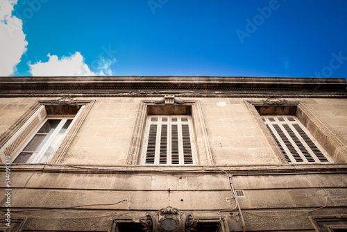 Facade of a typical old French residential building in Bordeaux, France, made of freestone, hosting flats, with a southwestern French architecture and some metal blinders.....