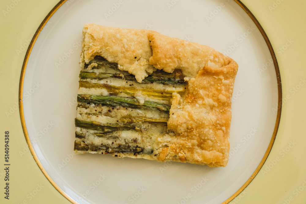 single serving, rectangular slice of an asparagus gruyere galette on golden yellow plate single serving, rectangular slice of an asparagus gruyere galette on golden yellow plate