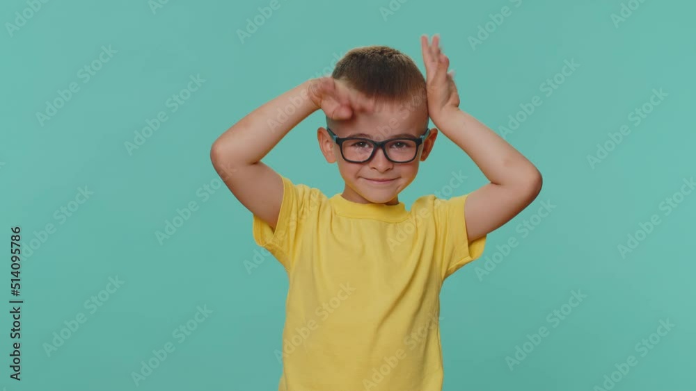 I am little bunny rabbit. Lovely funny little toddler children boy smiling friendly, doing bunny ears on head, having fun, fooling with humorous comical mood. Young one kid playing on blue background I am little bunny rabbit. Lovely funny little toddler children boy smiling friendly, doing bunny ears on head, having fun, fooling with humorous comical mood. Young one kid playing on blue background