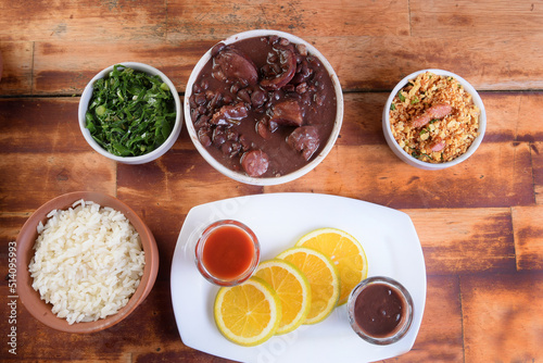 Feijoada typical Brazilian food, beans with pork bacon, orange rice and flour, chili sauce and crackling