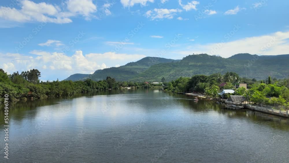 low flying backwards from a large river surrounded by green nature. Mountains as backdrop low flying backwards from a large river surrounded by green nature. Mountains as backdrop