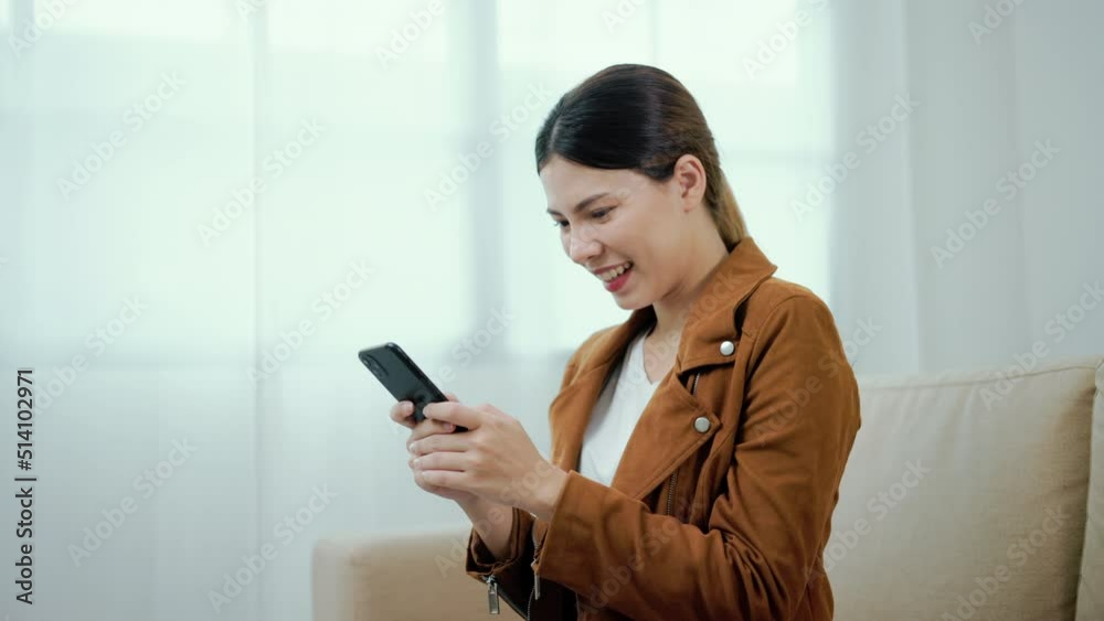 Wow. Happy beautiful woman surprise and excited when looking at mobile phone sitting sofa in living room at home. Successful female achieve their goals business. Smartphone concept.