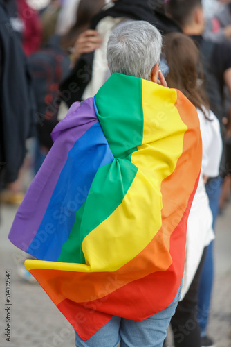 Older person with the LGBT flag on his back during the gay pride demonstration 
