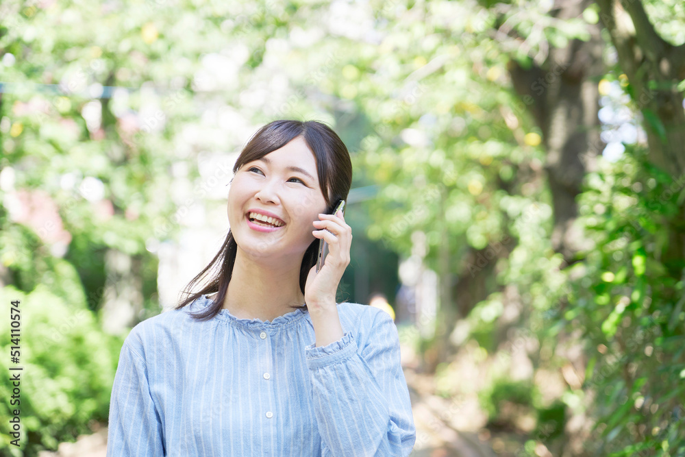 屋外での笑顔でスマホで電話する女性 屋外での笑顔でスマホで電話する女性