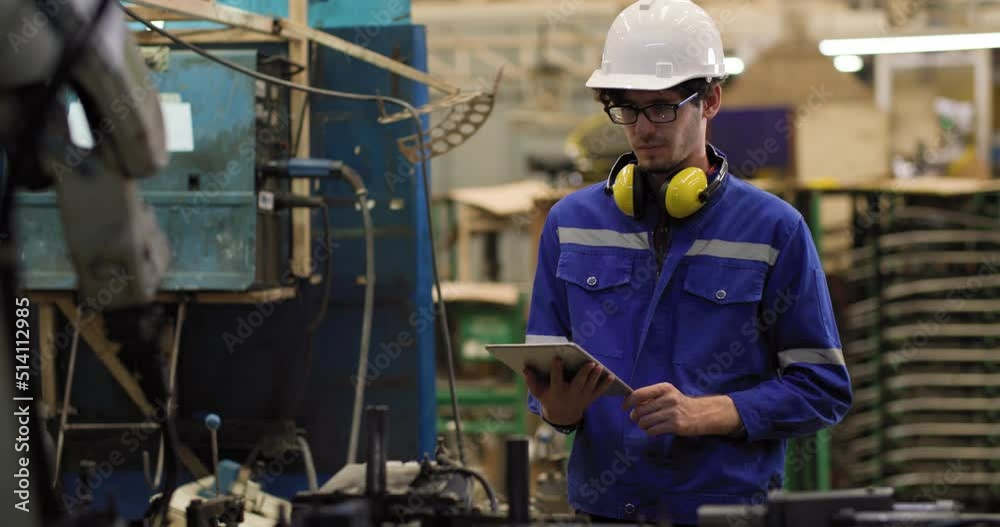 Professional industrial engineer caucasian man using digital tablet for programming control automation robot arms machine for composites material in manufacturing industry. Technology or innovation. Professional industrial engineer caucasian man using digital tablet for programming control automation robot arms machine for composites material in manufacturing industry. Technology or innovation.