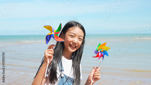 Smiling of little asian girl playing windmills outside on the beach together having fun enjoy freedom on summer vacation people lifestyle activity on weekend concept.
