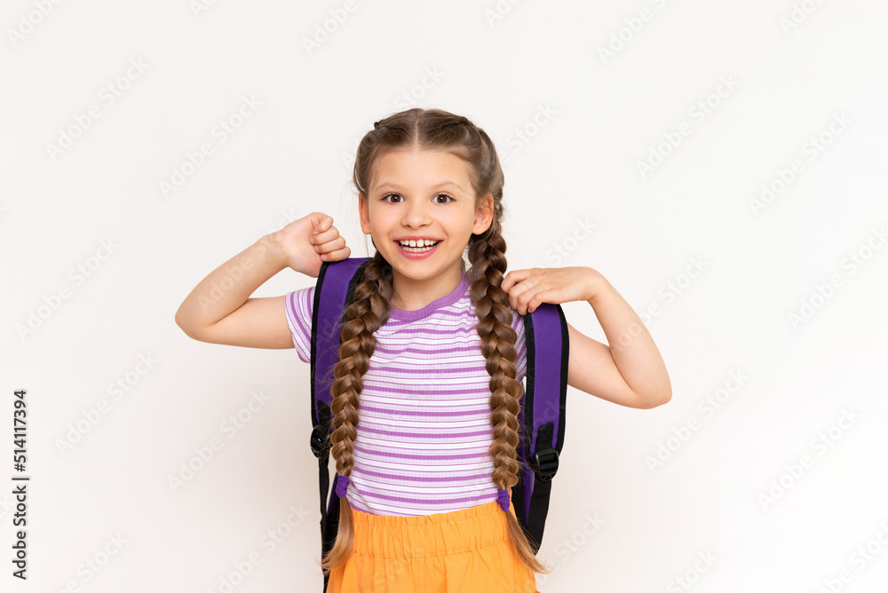 A little girl with pigtails and shorts with a school backpack on her back on a white isolated background. Preparatory summer courses for children. A little girl with pigtails and shorts with a school backpack on her back on a white isolated background. Preparatory summer courses for children.