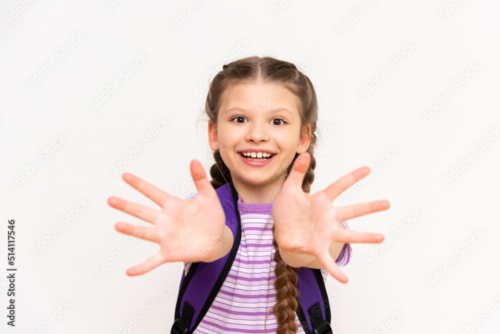 A child with a school backpack on his back pulls his hands forward on a white isolated background. A child with a school backpack on his back pulls his hands forward on a white isolated background.