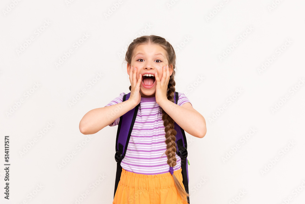 A little girl with a backpack on her back in orange shorts on a white isolated background. Summer educational courses for children. A little girl with a backpack on her back in orange shorts on a white isolated background. Summer educational courses for children.