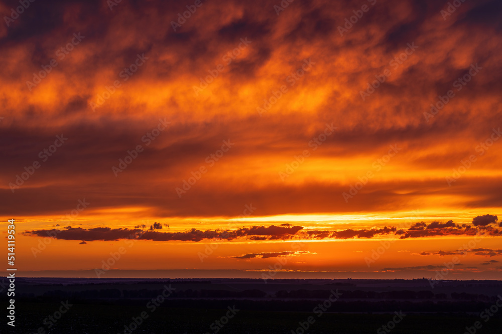 Sun sitting on the horizon against the background of colorful clouds in the sky Sun sitting on the horizon against the background of colorful clouds in the sky