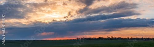 Fototapeta Naklejka Na Ścianę i Meble -  Sun sitting on the horizon against the background of colorful clouds in the sky 