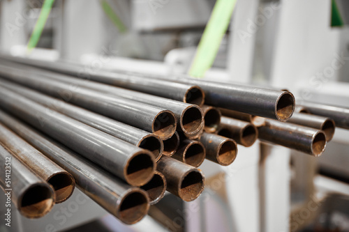 Stack of long metal pipes in metalworking plant warehouse