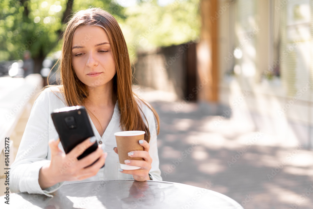 Image of serious young woman chatting on mobile phone while standing at street cafe outdoors Image of serious young woman chatting on mobile phone while standing at street cafe outdoors