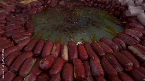 Spanish chorizo sausages stacked in circle around large frying pan, Closeup photo